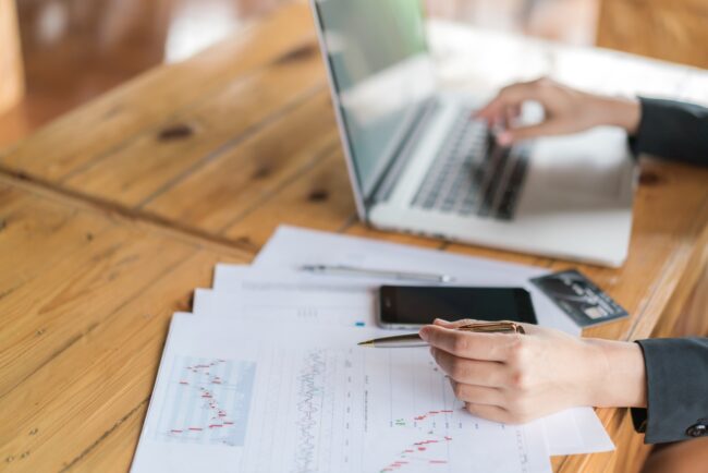 Business woman hand with Financial charts and laptop on the tabl